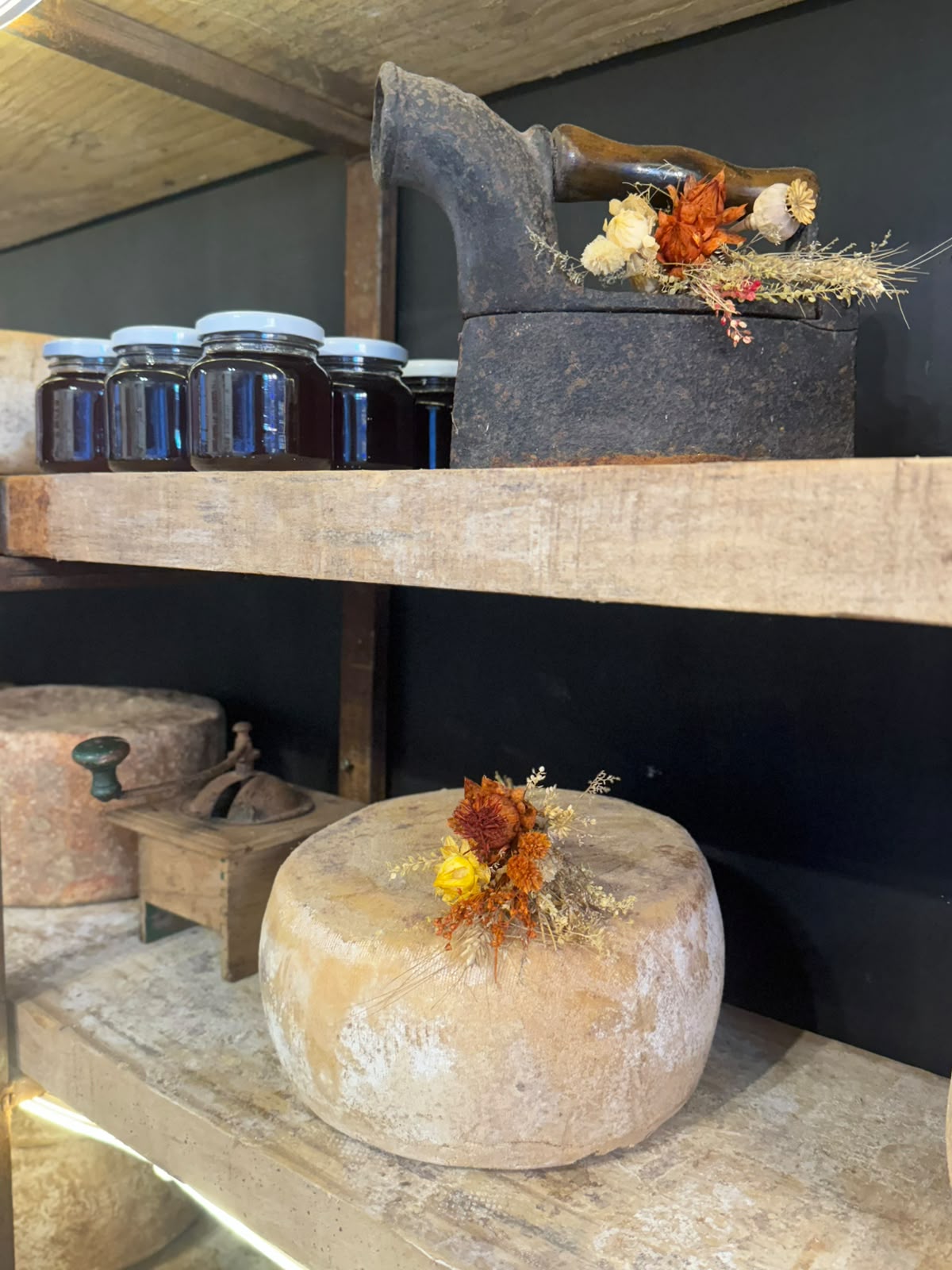 Estanteria con miel, queso y flores secas en el local