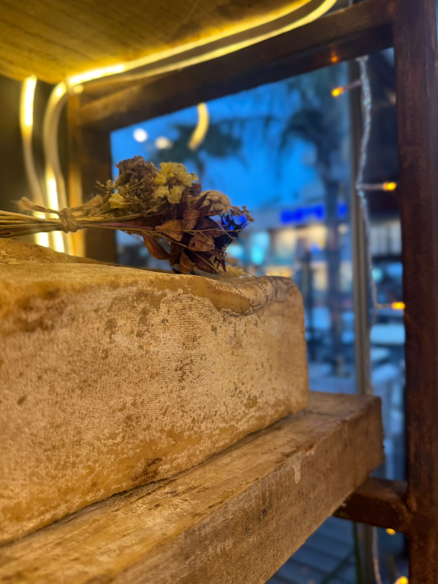 Queso artesanal en estante con flores secas y luces calidas